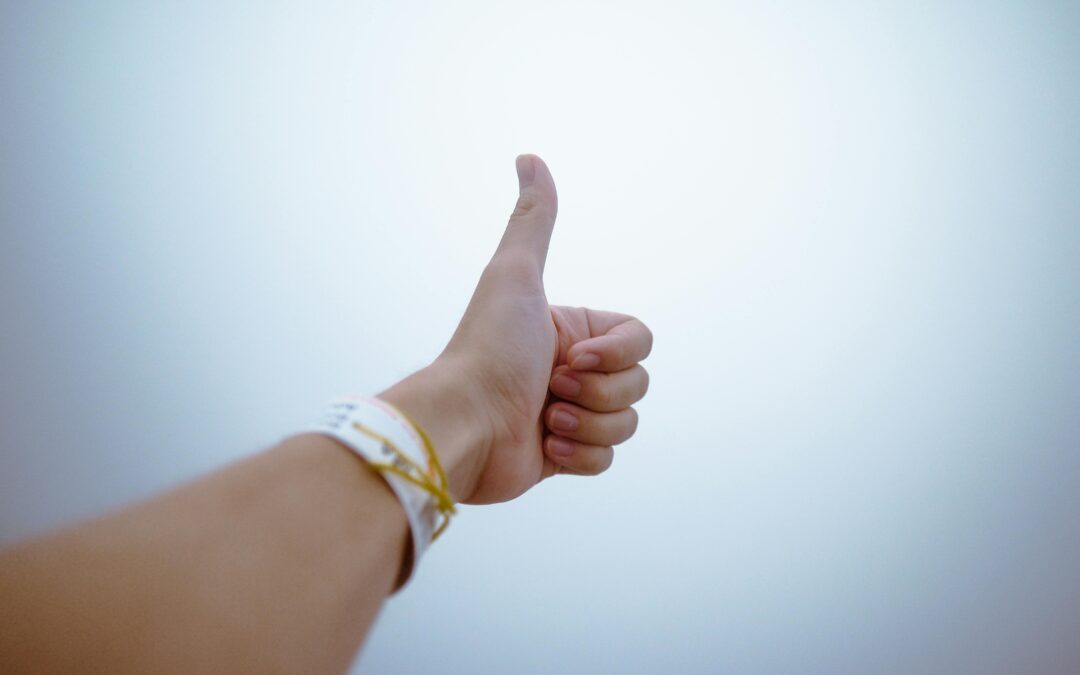 A hand giving a thumbs up gesture symbolizes approval and positivity.